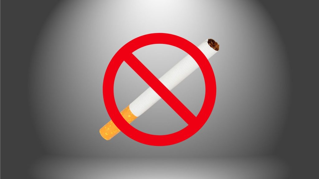 A forbidden sign over a cigarette on a gray background, illustrating the prohibition of smoking.