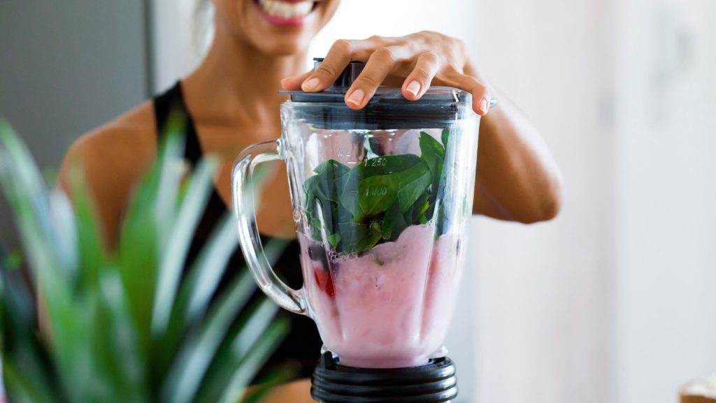 A person preparing a healthy smoothie in a blender, representing good nutrition and lifestyle choices after quitting smoking.
